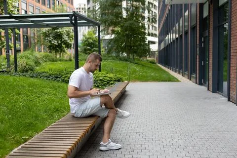 Sitting on the Internet. A serious student is sitting on a bench and looking at  Stock Photos
