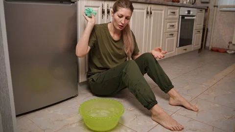 Sitting on the kitchen floor, she angrily throws a wet cloth Видео 303235156