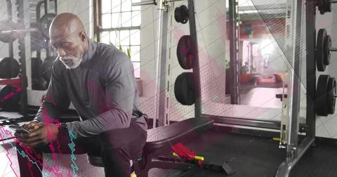 Sitting man checking phone on weight bench in gym, in long sleeve top, power Stock Photos