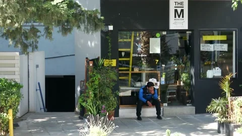 A sitting man in front of a coffee place Stock Footage 232872564