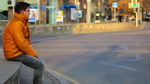Sitting man in an orange jacket with thoughtful look, on the background of Time Stock Footage 83636109