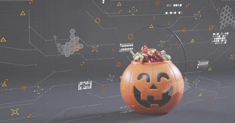 Sitting orange jack-o'-lantern bucket filled with foil candies on gray table, Photos