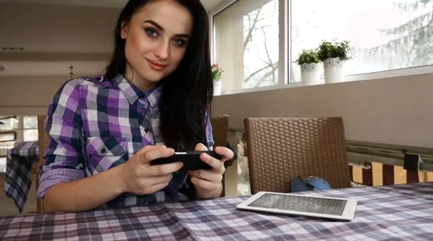 Sitting in the restaurant and using mobile phone. She looks into the camera Stock Footage 61407685