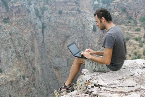 Sitting on rock and using laptop Stock Photos