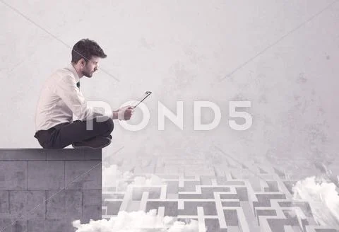 Sitting salesman on rooftop solving maze Stock Photos