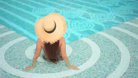 Sitting in the shallow end of the pool with her back to the camera, a Video stock 149545919