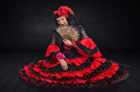 Sitting on stage flamenco dancer hiding her face by fan Stock Photos