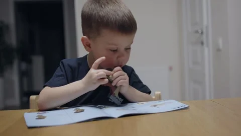 Sitting at table young child playing toy constructor following instructions Stock Footage 275750688