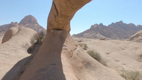 Sitting under the famous stone arch of Spitzkoppe National Park in Namibia Video stock 193988503