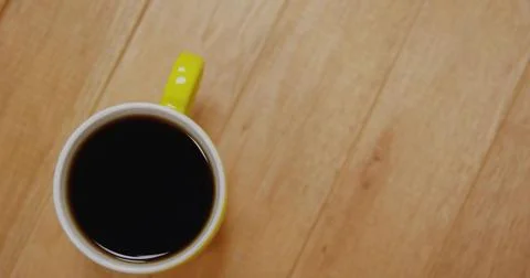 Sitting yellow-handled ceramic mug showing coffee glint on light wood tableto Stock Illustration