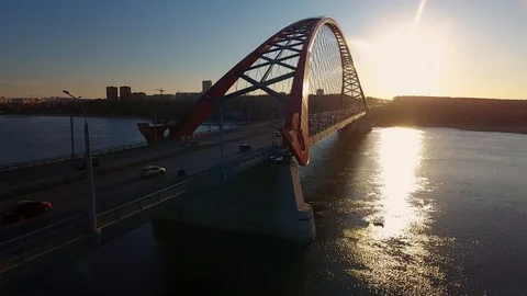 Сity at sunset. In foreground is bridge over river, along which cars are moving Stock Footage 104646609
