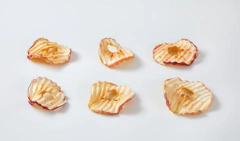 Six apple chips with seeds on plain background Stock Photos
