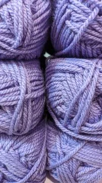 Six balls of purple wool thread folded in a row of two Stock Photos