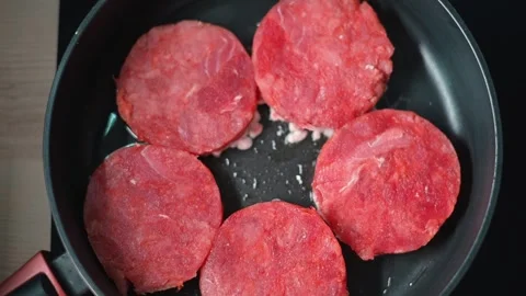 Six beef patties are placed in a skillet for cooking. Stock Footage 338304072