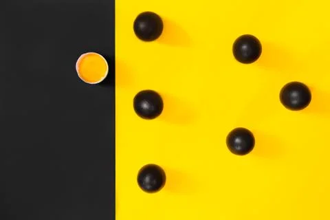 Six black eggs withe one broken egg on a black background with yellow, pop ar Stock Photos