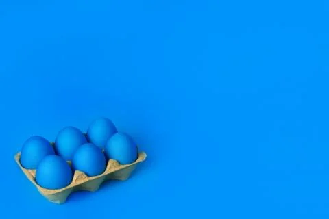 Six blue painted Easter eggs in yellow wrapping on blue background. Foto stock