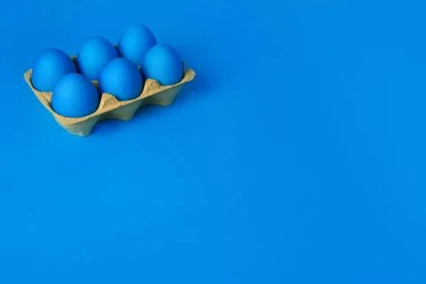 Six blue painted Easter eggs in yellow wrapping on blue background. Happy Easter Stock Photos