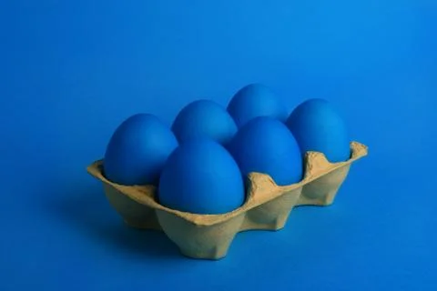 Six blue painted Easter eggs in yellow wrapping on blue background. Happy Easter Stock Photos