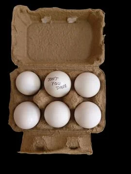 Six eggs in a tray and one of them has a slogan as "Don't you dare" Foto stock