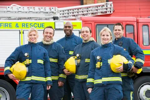 Six firefighters standing by fire engine Stock Photos