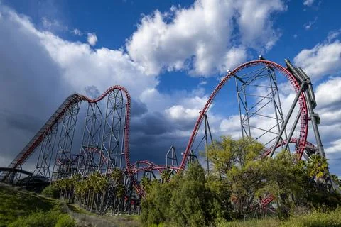 Six Flags Magic Mountain, roller coaster beautiful storm clouds, green landscape Stock Photos