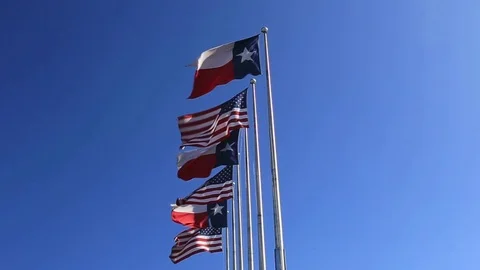 Six Flags over Texas: American and Texas Flags fluttering against blue sky Video stock 72452277