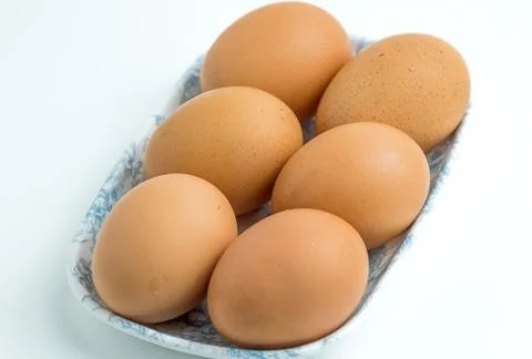 Six fresh brown chicken eggs arranged in a small container isolated on whit.. Stock Photos