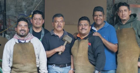Six friendly smiling Mexican men looking at the camera in their workshop Stock Footage 102721231