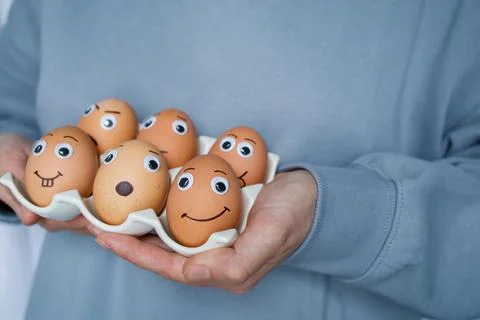 Six funny handmade Easter emoji eggs on a stand in woman hands close up. Ch.. Stock Photos