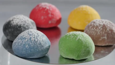 Six mochi cakes spin while lying on a mirror surface. Presentation of flavors. Video stock 237396994