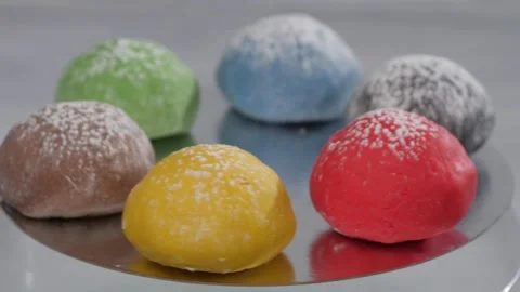 Six mochi cakes spin while lying on a silver surface. Presentation of flavors. Video stock 252879743