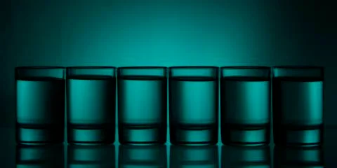 Six small multi-colored glasses on a bright background 스톡 사진