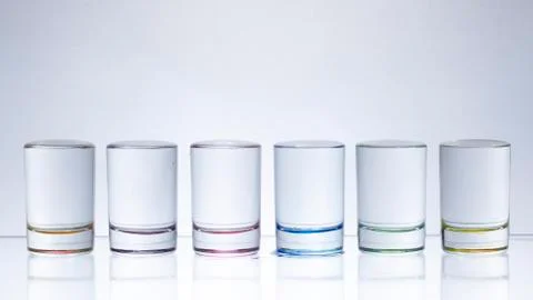 Six small multi-colored glasses on a bright background Stock Photos