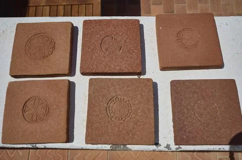 Six square clay bricks with different geometric and floral patterns laid on a Stock Photos