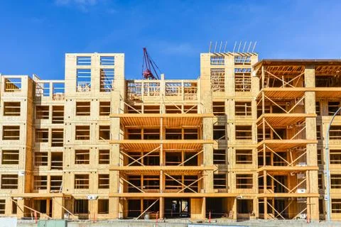 Six storey frame building under construction on concrete foundation bed. Stock Photos