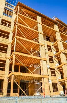 Six storey frame building under construction on concrete foundation bed. Stock Photos