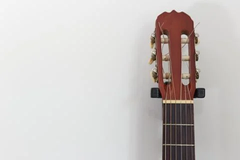 Six-string guitar hanging using wall mount. over white background. with copy  Foto stock