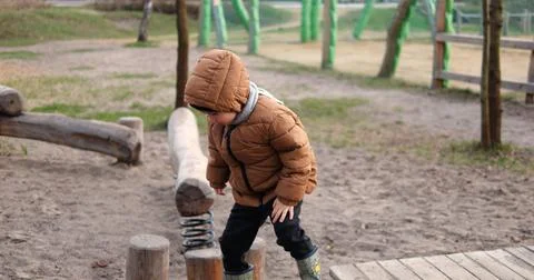 Six year boy cautiously moves on stepping logs on wooden playground in autumn. Stock Photos