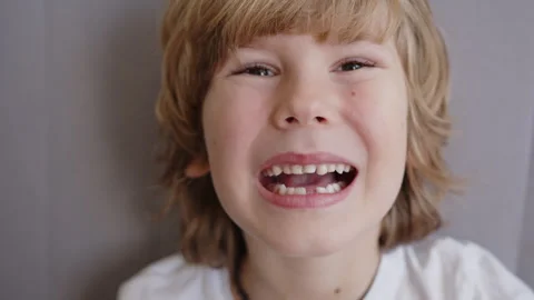 Six year old boy excitedly checks his loose upper incisor baby teeth with his Vidéo 337643016