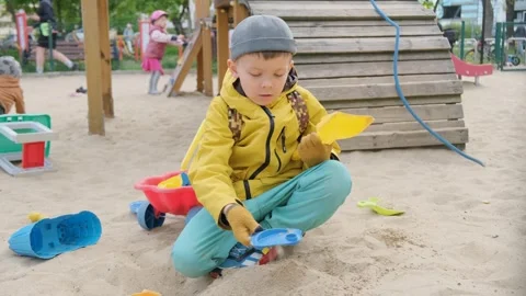 Six-year-old boy playing with sand on children's playground Video stock 240308656