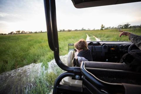 A six year old boy riding in safari vehicle looking out over the landscape Stock Photos