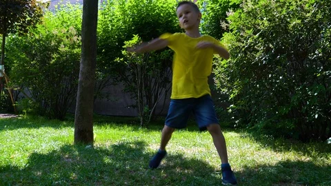 A six-year-old child is boxing in a yellow T-shirt in the park. Stock Footage 109568720