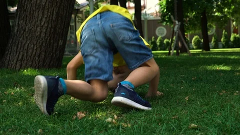 A six-year-old child tumbles on a lawn in the park. Stock Footage 109572980