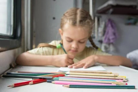 Six year old girl draws a pencil in a notebook for a side table in the second Stock-Fotos