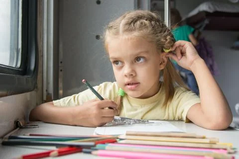 Six year old girl draws a pencil in a notebook for a side table in the second Stock Photos