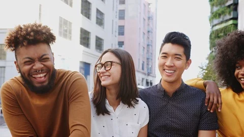 Six young adult multi-ethnic friends in a row on a city street laughing, waist Stock Footage