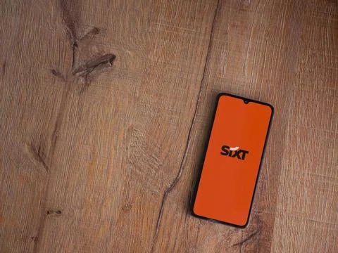 SIXT rent app launch screen on smartphone on wooden background Stock Photos