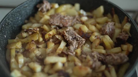 Sizzling beef and potato slices browning in a frying pan Stock Footage 333580489