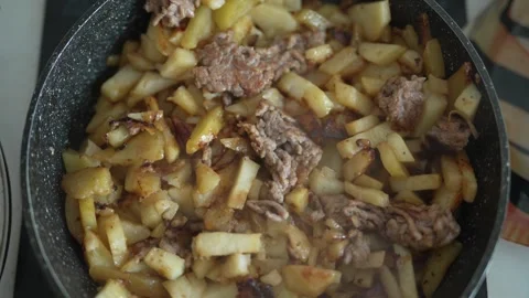 Sizzling beef and potato slices browning in a frying pan Stock Footage 333580490