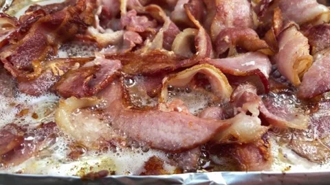 Sizzling brown Bacon strips. slices of bacon cooking on aluminum foil. 스톡 동영상 334642267